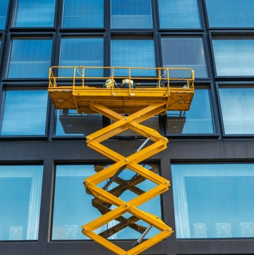 piattaforma elevatrice industriale a pantografo utilizzata per raggiungere i piani più alti dell'edificio in vetro